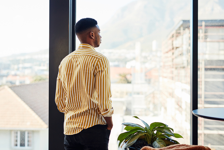 young black man looking out of window